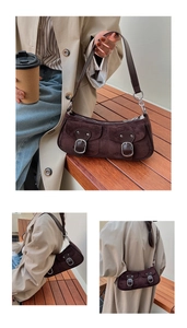 Détails du sac croissant en daim marron foncé avec boucles métalliques sur escalier en bois