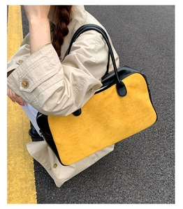 Detail of a yellow and black boston bag made of suede and leather on an outdoor model