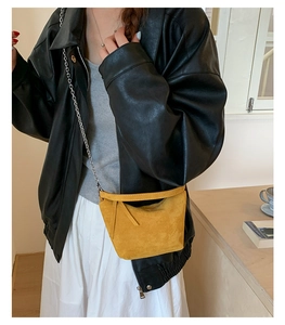 Bright yellow suede crossbody bag with silver chain strap worn by a female model
