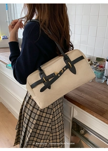Minimalist cream shoulder bag with black leather straps and gold metal hardware