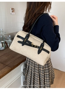 Detail of off-white suede shoulder bag with black strap and golden buckle accent