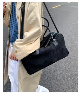 Close-up of a large black suede tote bag shown on a model in a beige trench coat for daily use