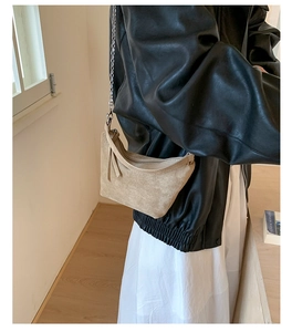 Macro view of light beige suede crescent bag showing refined leather texture and chain