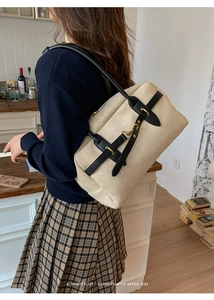 Detail shot of a minimalist retro cream suede handbag with black straps and gold hardware