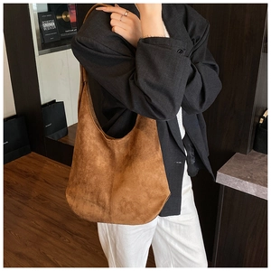 Brown matte hobo tote bag worn by a model in a minimal modern indoor setting