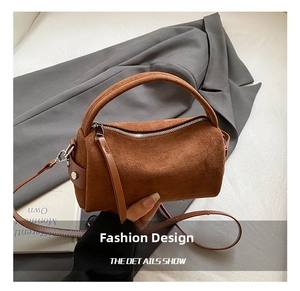 Detail einer braunen matten Zylindertasche aus Leder mit Reißverschluss und Trageriemen