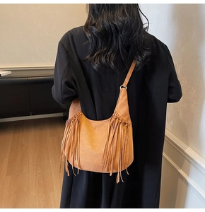 Vue détaillée du sac hobo en daim marron avec de longues franges bohèmes sur l'épaule