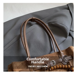 Dettaglio del manico in camoscio marrone con perla di legno e cinturino in pelle