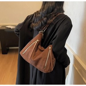 Dettaglio della borsa tote in pelle scamosciata marrone con cerniere e lunghe frange