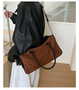 Detailed view of brown suede and black leather patchwork tote bag on shoulder