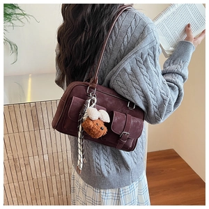 Detail of vintage burgundy Boston shoulder bag with plush bear charm and pockets