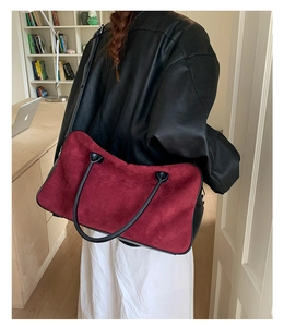 Chic burgundy suede tote bag with black leather handles shown in a lifestyle setting