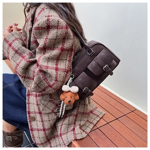 Detail view of a vintage dark brown multi-pocket handbag with a cute teddy bear charm