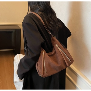 Detail of dark brown faux suede hobo bag with long fringe zippers on a model