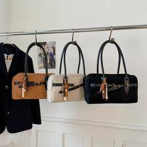 Three retro suede handbags in brown, beige and black hanging on a display stand