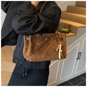 Dettaglio della borsa tote vintage in pelle scamosciata marrone con pendente di perline