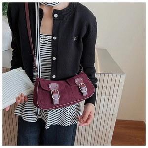 Detalle de bolso bandolera de ante burdeos con dos bolsillos de solapa y hebillas plata