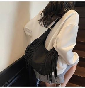 Détail du sac hobo noir avec longues franges et texture daim porté par un mannequin