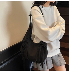 Détail du sac hobo en daim noir avec de longues franges et des boucles en métal doré