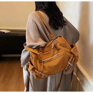 Detail of vintage brown tote bag showing multi-zipper pockets and moto style buckled straps
