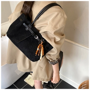 Detail of a vintage black frosted tote bag featuring bead tassels and leather strap buckle