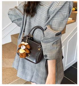 Détail du sac seau marron foncé en simili cuir avec breloque ours et logo doré OIN DH