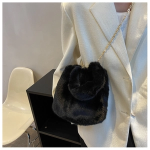 Détail du sac seau en peluche noire avec une élégante bandoulière chaîne dorée