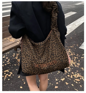 Detailed close-up of leopard print hobo bag with elastic strap and embroidered logo text