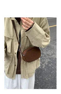Detail of dark brown suede crossbody bag showing textured fabric and smooth leather edges