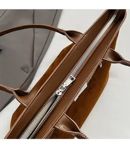 Detailed top view of the brown suede tote bag featuring a smooth silver metal zipper