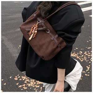 Dettaglio della borsa tote in pelle scamosciata marrone scuro con fibbia vintage e nappa