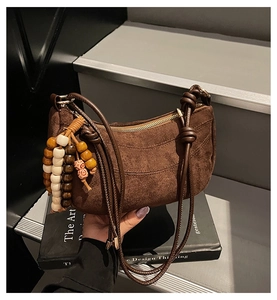 Detailansicht braune Wildleder-Tasche mit dekorativer Holzperlen-Quaste und seitlichen Knoten