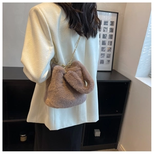 Détail d'un sac seau en fausse fourrure marron avec une bandoulière chaîne dorée