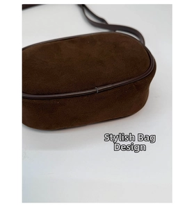Detail of dark brown suede crossbody bag with rounded edges and vintage minimalist design