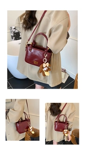 Détail du sac seau bordeaux avec texte doré et un petit pendentif ours en peluche