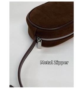 Detailed close-up of premium silver hardware zipper on a brown suede shoulder bag