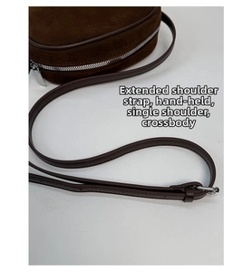 Close-up of brown suede bowling bag featuring silver zipper and adjustable strap