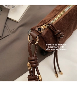 Close-up of luxury dark brown suede bag with premium gold metal zipper and hardware details