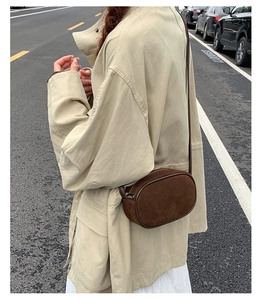 Detail of dark brown suede shoulder bag worn by model in a street style setting