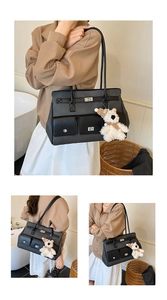 Macro shot of minimalist black tote bag featuring functional pockets and plush bear charm