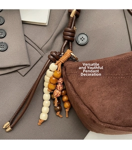 Detail of brown suede dumpling bag featuring bohemian style wooden beaded charm