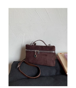 Detail of dark brown suede handbag featuring silver metal zipper and padlock decor