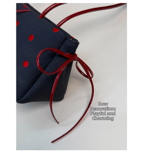 Dettaglio borsa blu navy a pois rossi con un fiocco di nastro rosso lucido