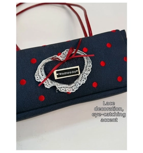 Dettaglio borsa in denim blu con pois rossi e toppa a cuore con pizzo