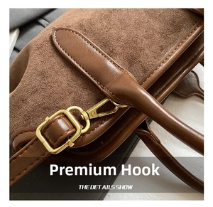 Close-up of golden metal hooks and premium brown suede texture on a tote bag