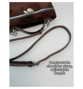 Detail of adjustable shoulder strap and silver metal buckle on brown suede square bag