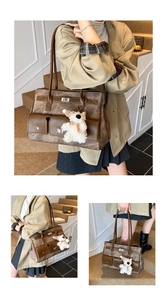Close-up of vintage brown leather handbag featuring metal buckles and a cute plush bear charm