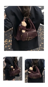 Dettaglio borsa tote in pelle scamosciata marrone scuro con cinghie retro e ciondolo orso