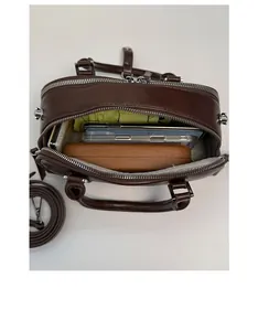 Vista interior del bolso vintage de cuero marrón con espacio para móviles y cartera larga