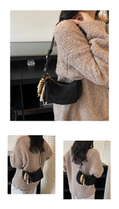 Detail of black crescent suede bag with knot strap and bohemian wooden bead tassels